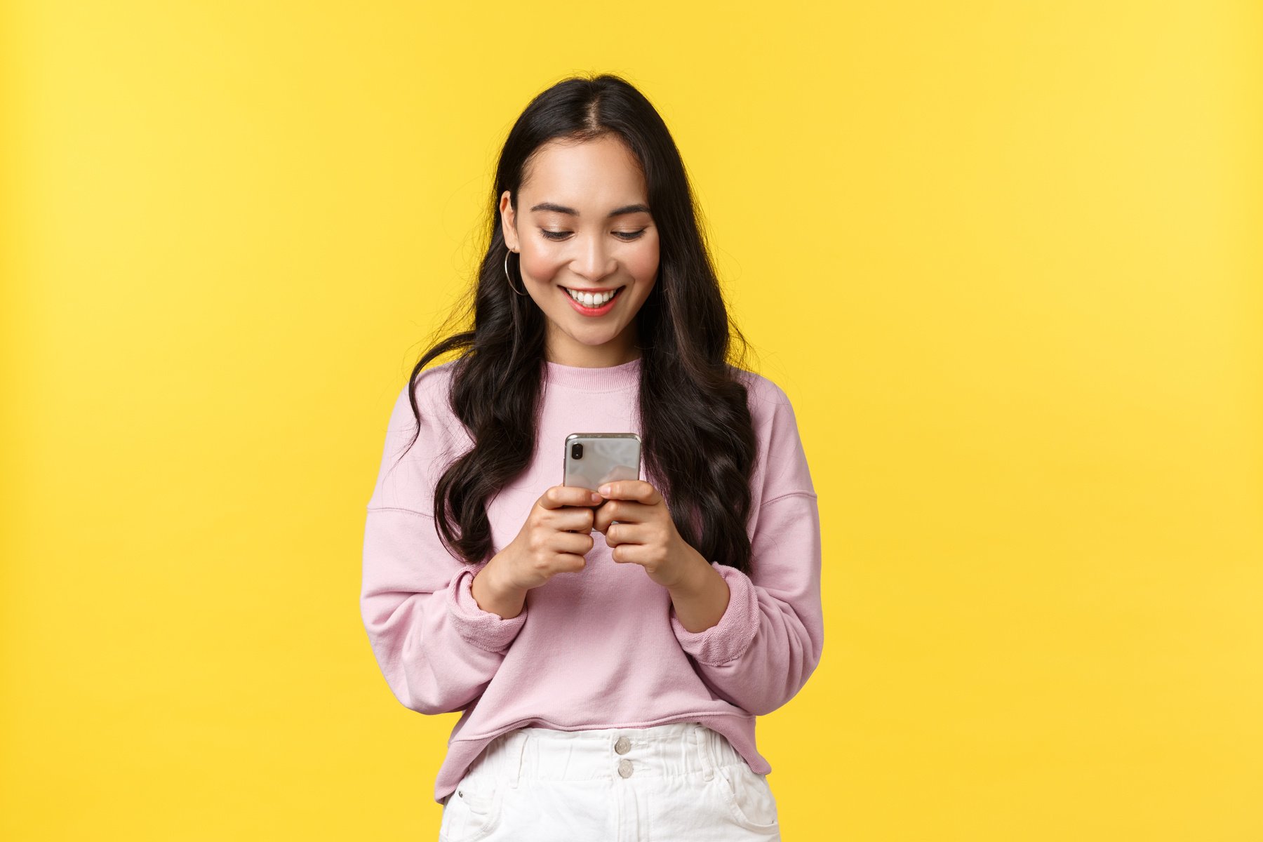 People Emotions, Lifestyle Leisure and Beauty Concept. Young Modern Asian Girl Blogger Make Post on Social Media Using Smartphone App, Messaging, Looking at Mobile Phone with Pleased Smile